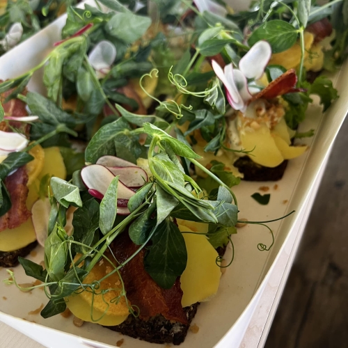 Smørrebrød med kartoffel, sprødstegt bacon, radiser og ærteskud – kan fås som take-away i Sæby.
